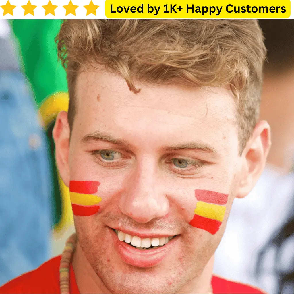 Man with Spanish flag Custom Tattoo – Your Design, Your Statement 🎨 on cheeks, surrounded by a blurred crowd with a flag in the background.