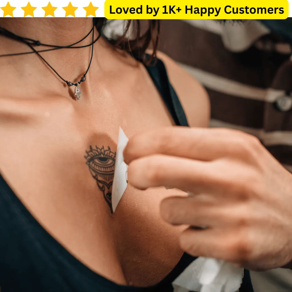 Person cleaning a tattoo with a white cloth, surrounded by text about customer satisfaction. Fake Tattoos Custom – Your Design, Your Way