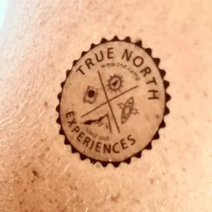 Circular logo with 'True North Experiences' text on a textured surface