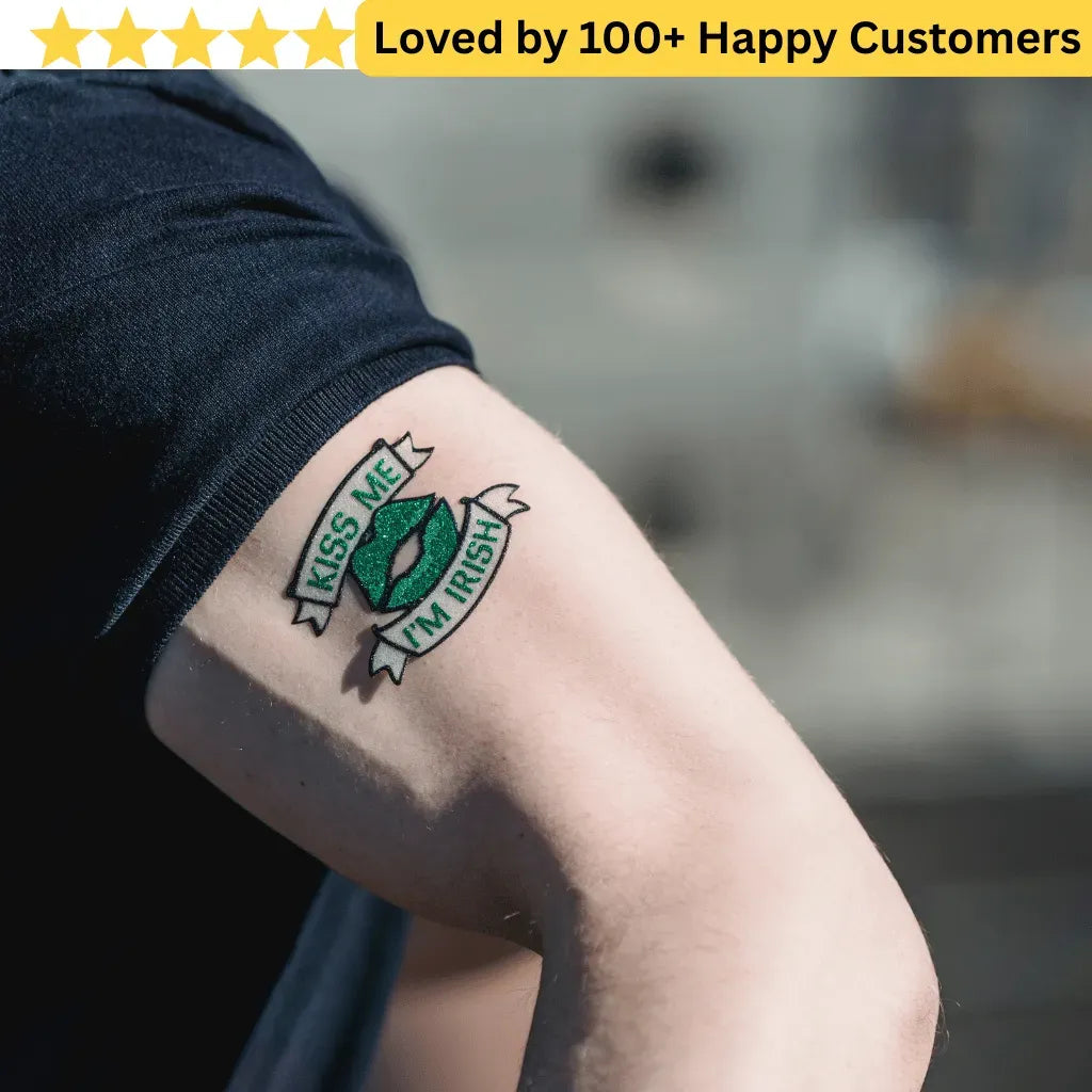 Tattoo on a person's arm with 'Kiss me, I'm Irish' design, set against a blurred outdoor background.