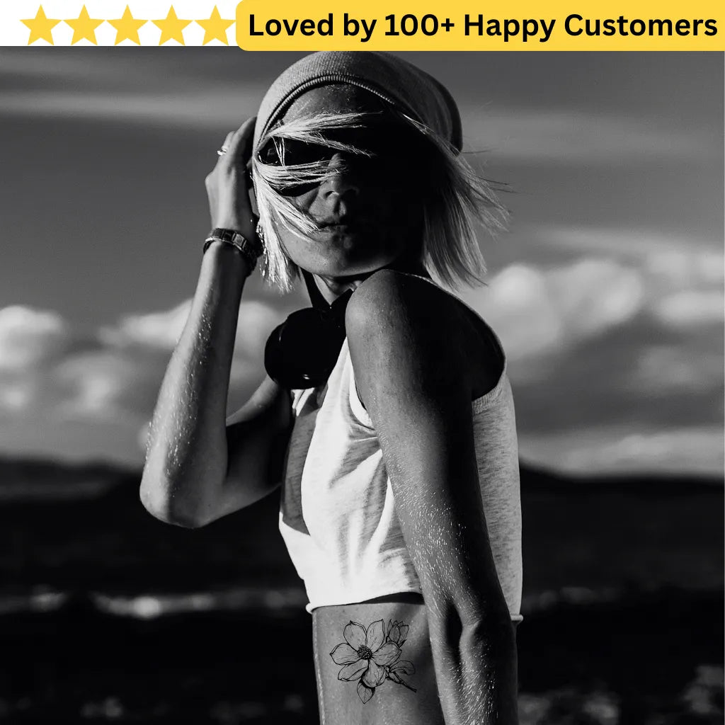Black and white photo of a person with a tattoo against a mountainous background, with text 'Loved by 100+ Happy Customers' at the top. Floral Tattoo Designs