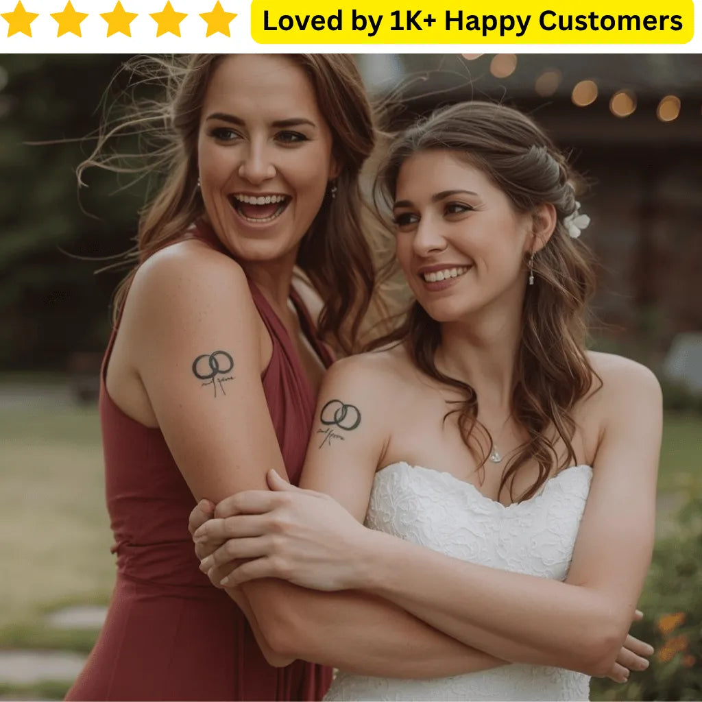 Two women with matching tattoos on their arms, standing close together outdoors. Test your wedding ring design with a temporary tattoo before making it permanent. Explore wedding tattoo ring designs for couples, guests, and stylists—printed locally in South Africa