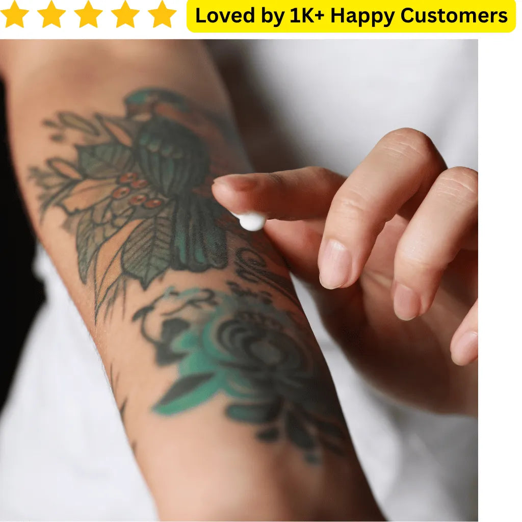 Tattoo on a person's arm with a hand holding a white object, above text 'Loved by 1K+ Happy Customers'. Express your style with bold, skin-safe tattoos—perfect for fashion-forward women