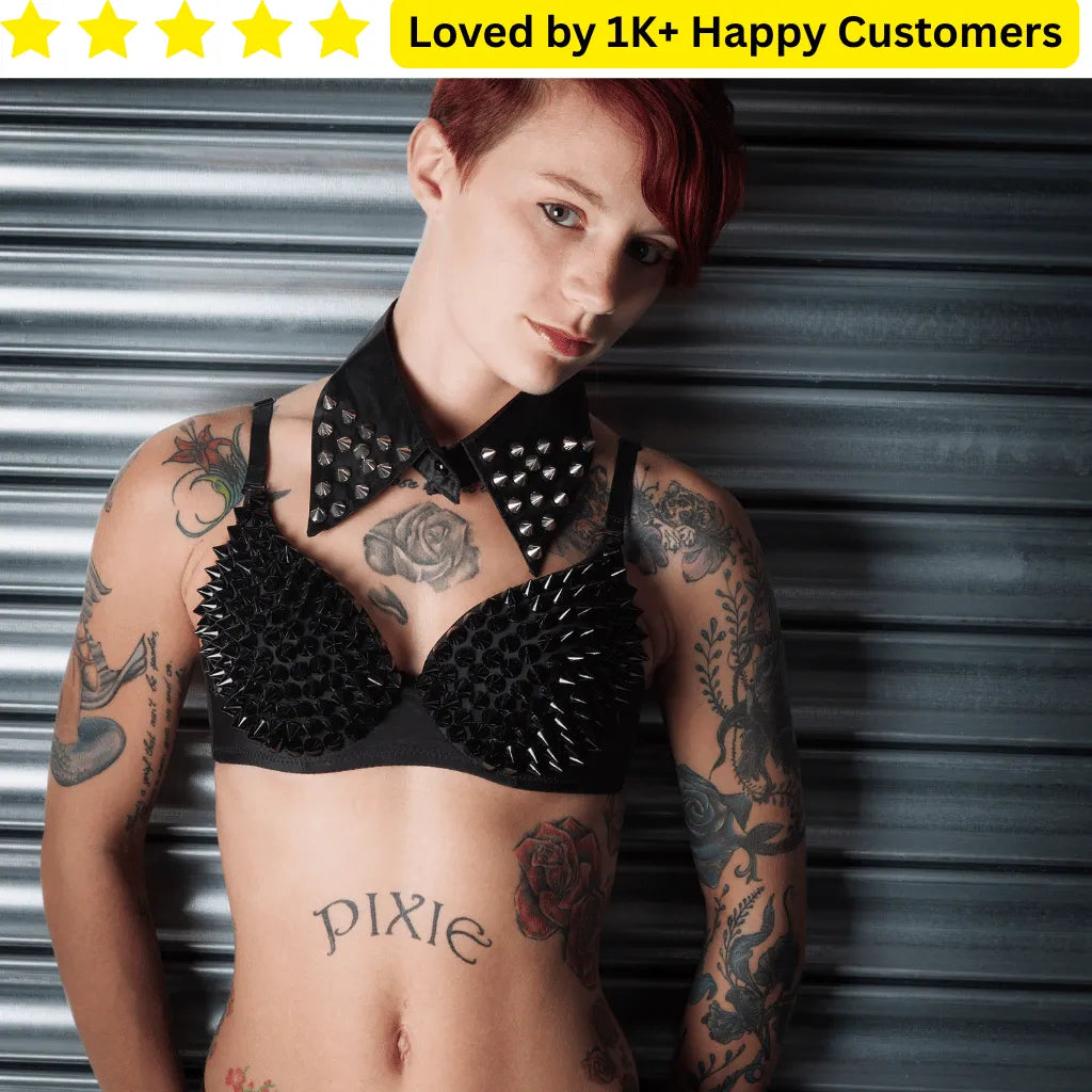 Person wearing a black spiked bralette with tattoos visible, against a metallic background. Goth Tattoo – Upload Your Artwork & Get in 3 Days