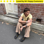 Person sitting on a step wearing tan pants and black shoes with yellow accents, with a brick wall and door in the background. Goth Tattoo – Upload Your Artwork & Get in 3 Days