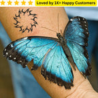 Blue butterfly on a person's arm with a tattoo, set against a blurred background. Men's Tattoos Arm for Testing Your Next Tattoo