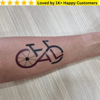 Tattoo of a bicycle on a person's arm with text 'Loved by 1K+ Happy Customers' above.