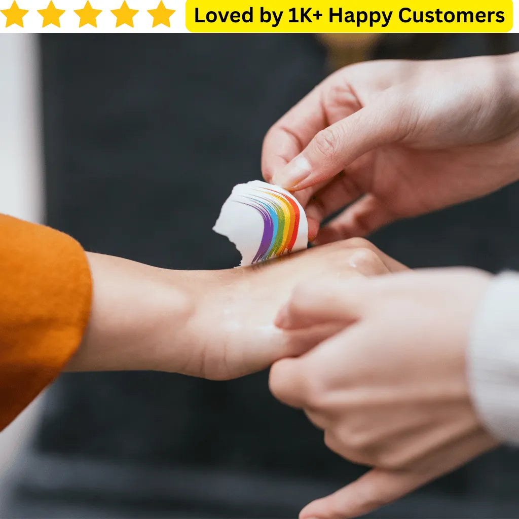 Person applying a rainbow-colored temporary tattoo to another person's arm. Branded Temporary Tattoos: Upload your Logo, Slogan, or Campaign Design – No Bulk Lock-In