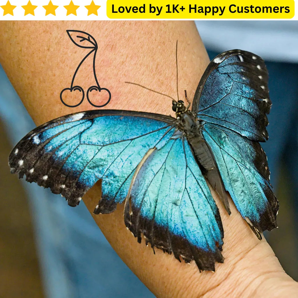 Blue butterfly on a person's arm with a tattoo of a cherry, set against a blurred background. Bold, Skin-Safe Tattoos for Women Who Love Fashion Without the Commitment&nbsp;
