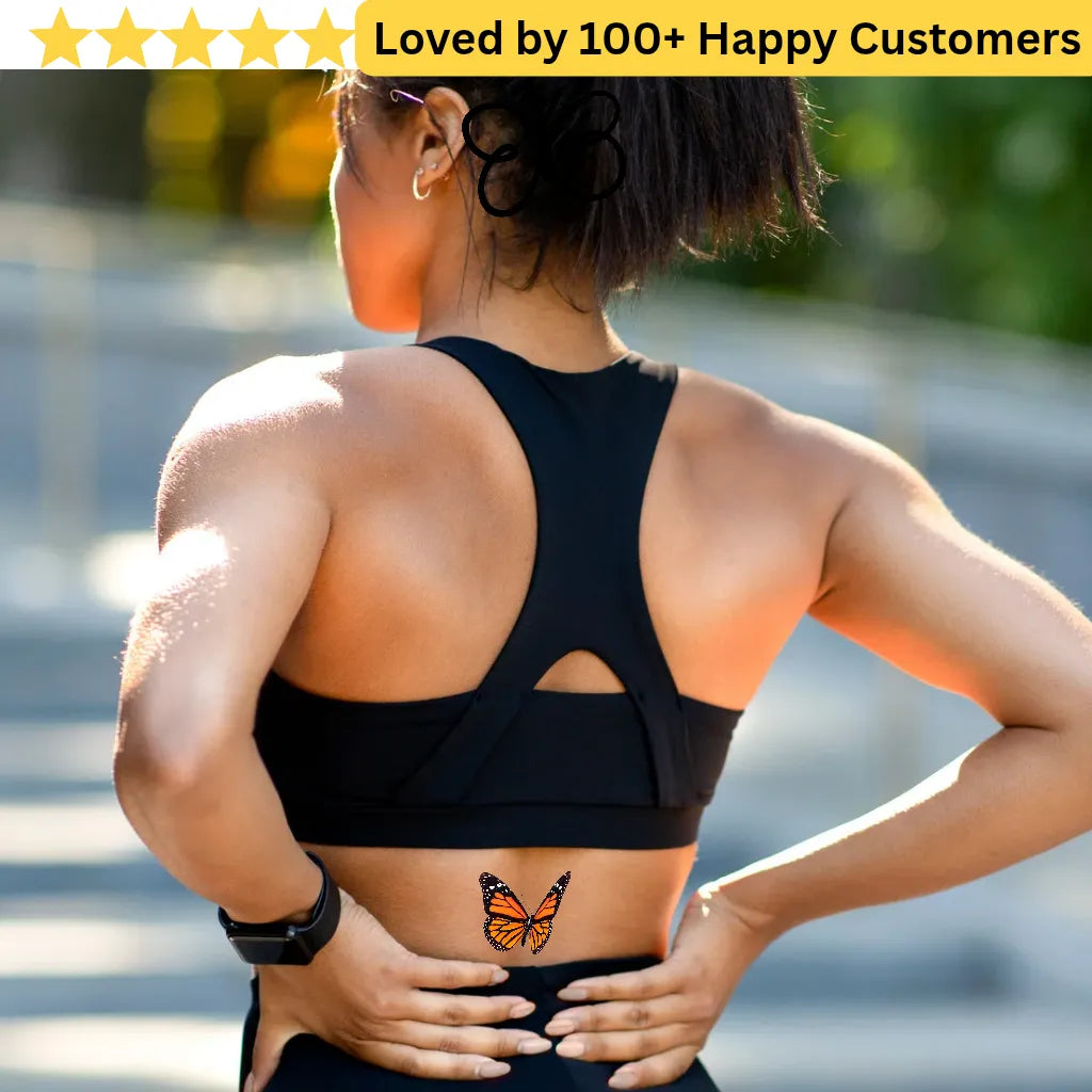 Person wearing a black sports bra with a butterfly tattoo outdoors. Lower Back Tattoos Womens – Feminine & Flirty