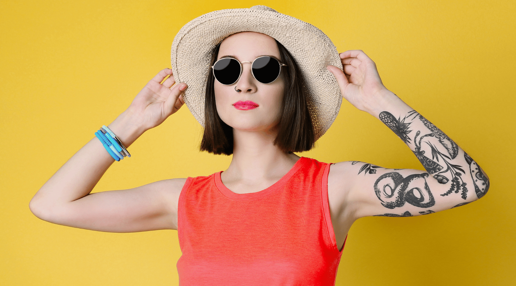 Woman wearing a straw hat and sunglasses against a yellow background